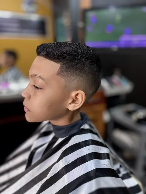 Corte infantil com degradê e o cabelo penteado para trás