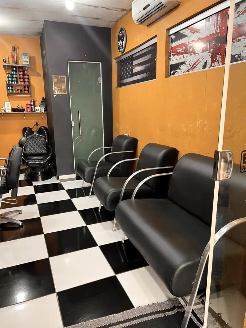 As poltronas de espera de couro preto, no salão de parede amarela e piso xadrez